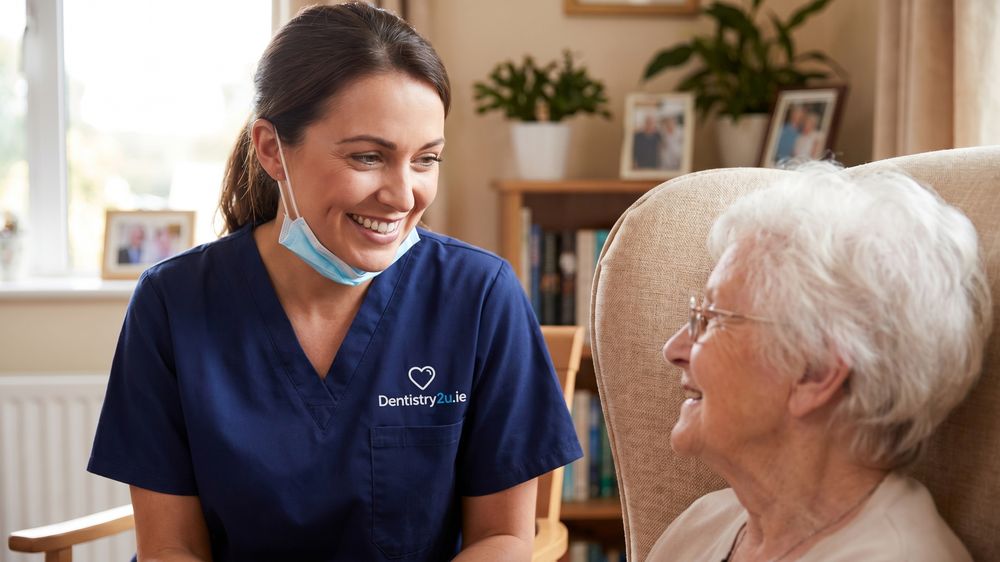 A dentist talking with an older woman in her own sitting room before an examination